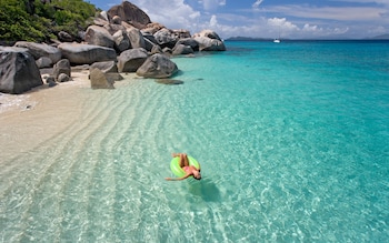 person in green rubber ring in a blue, still sea