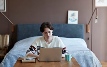 Young woman in her bedroom working at her desk on investments