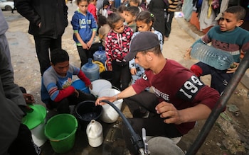 Palestinian children wait with bottles in line to get water amid clean water and food crisis from mobile storages of charities as they have limited access to water