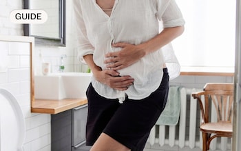 A woman holding her belly in the bathroom