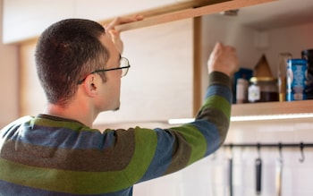 Man reaching for ingredients in kitchen cupboard