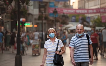 A man and woman walking along wearing face masks